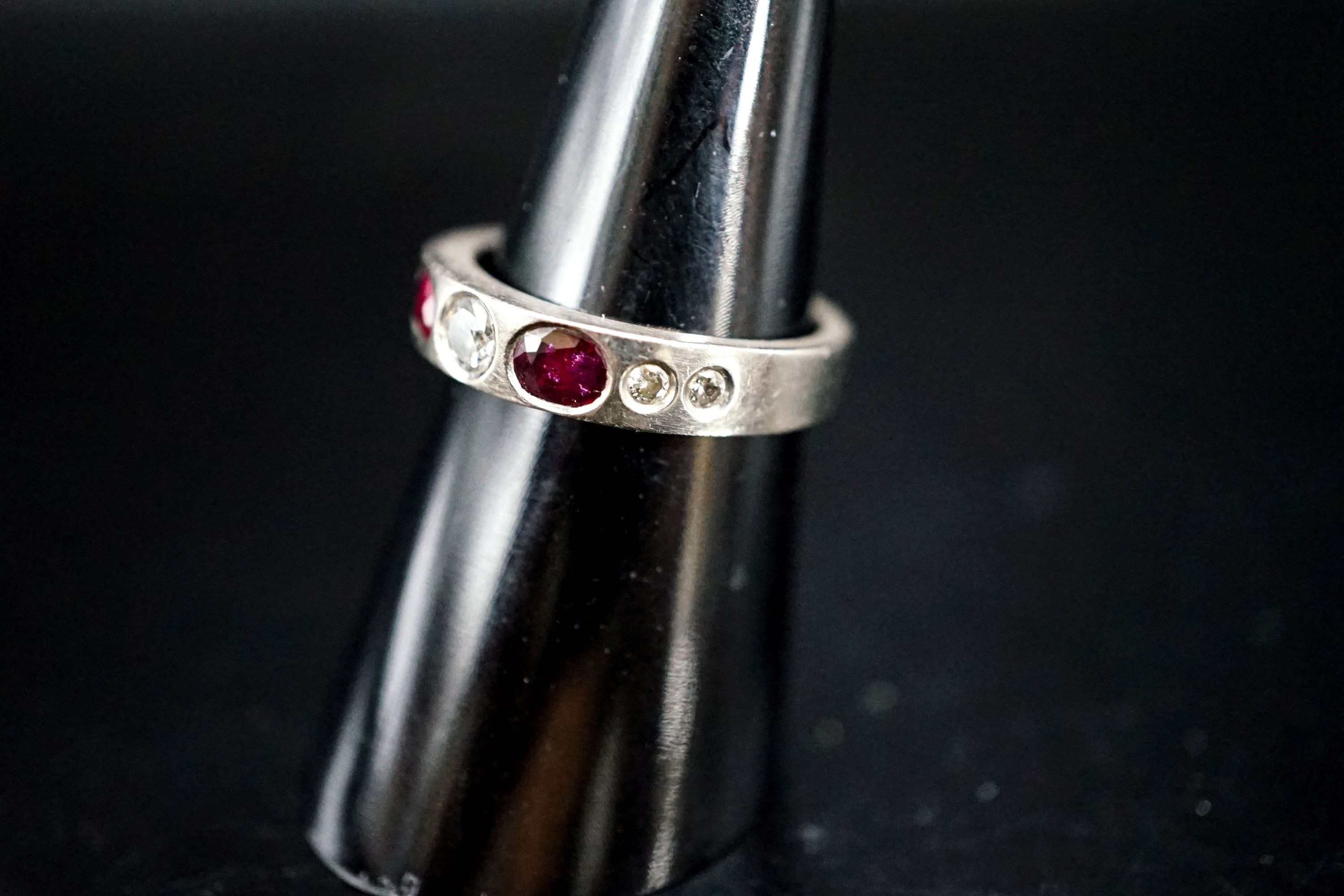 A white metal and gypsy set ruby and diamond set half hoop ring, size M, gross 6.1 grams.